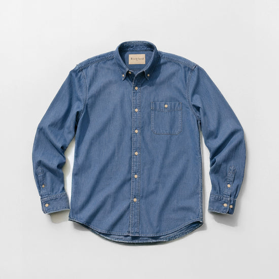 Bickford USA Denim Field Shirt in medium wash chambray denim, flat lay front view, featuring a button-down collar, single chest pocket with button flap, cream buttons down the placket, and button cuffs, against a light gray background.