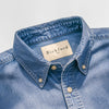 Close-up detail of the Bickford USA Denim Field Shirt collar, showing the button-down collar points with cream buttons, contrast stitching, and a cream Bickford USA woven label at the neck, against a light gray background.