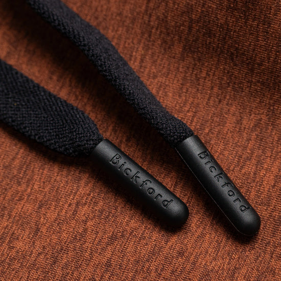 Close-up of Bickford engraved black drawstring tips on Rust athletic jogger fabric