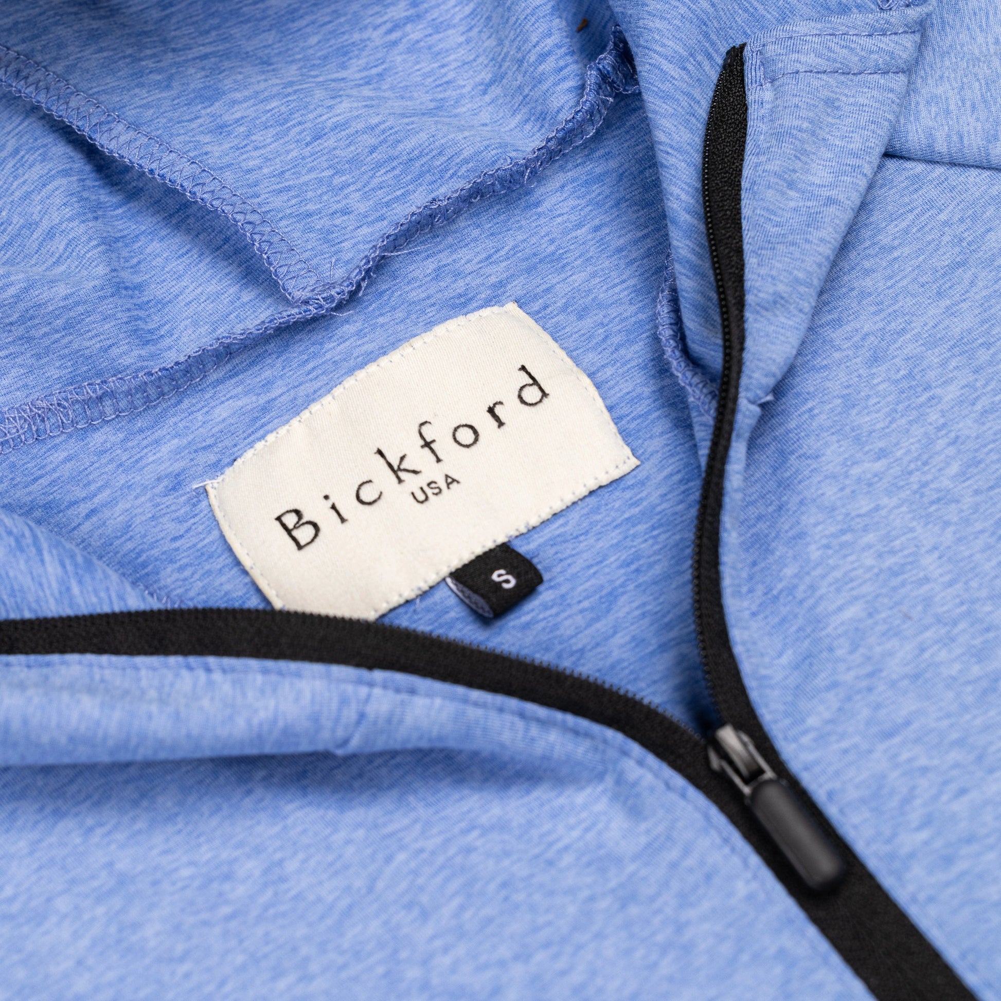 Close-up of Bickford USA woven label and black quarter zipper on Blue Bird hoodie
