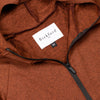 Close-up of Bickford USA woven label and black quarter zipper on Rust hoodie