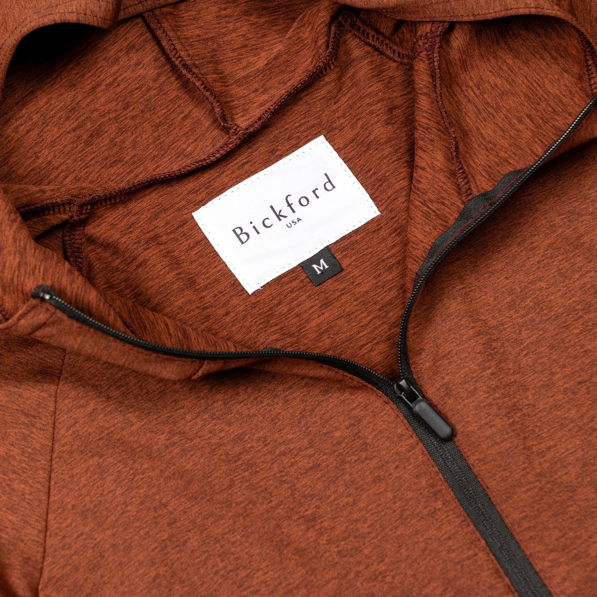 Close-up of Bickford USA woven label and black quarter zipper on Rust hoodie
