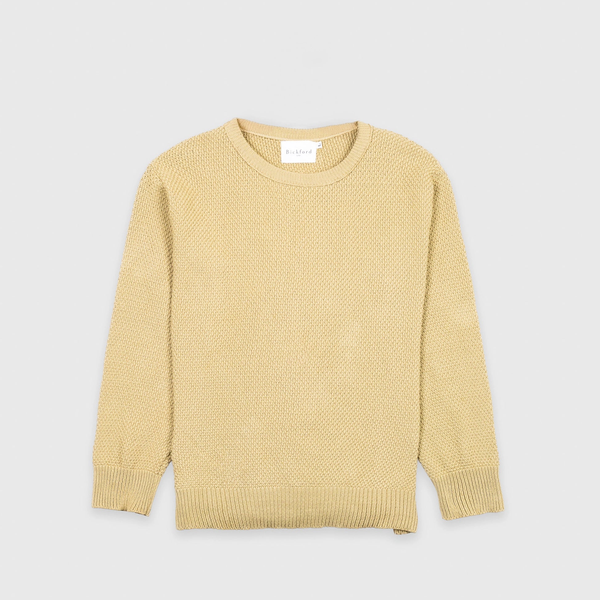 Bickford USA Fisherman Crewneck sweater in cream, laid flat on a light gray background, showing the full front with seed stitch knit texture and ribbed crew neck, cuffs, and hem.