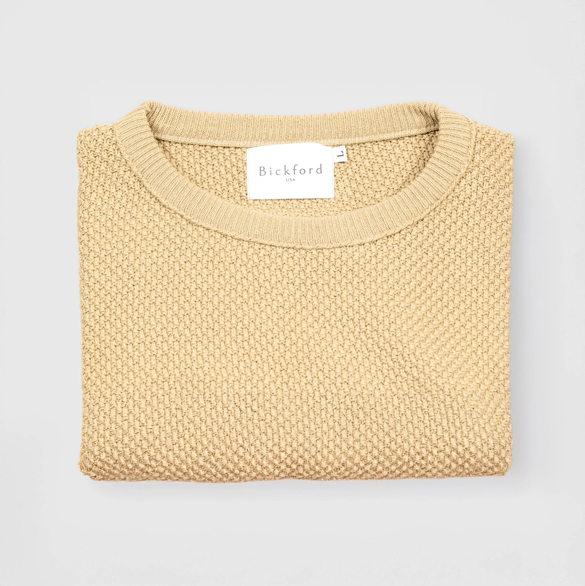 Bickford USA Fisherman Crewneck sweater in cream, neatly folded and photographed from above, with the Bickford USA label visible at the center of the neckline.