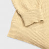 Extreme macro close-up of the cream Fisherman Crewneck fabric, showing the chunky seed stitch knit texture and natural yarn fibers in detail.