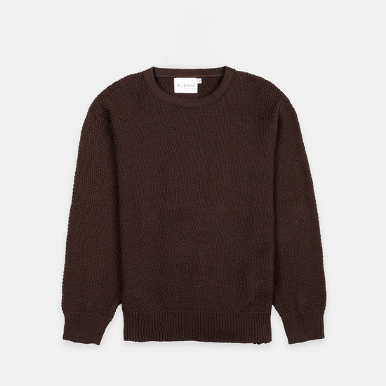 Bickford USA Fisherman sweater in dark brown, laid flat on a light gray background, showing the full front with seed stitch knit texture and ribbed crew neck, cuffs, and hem.