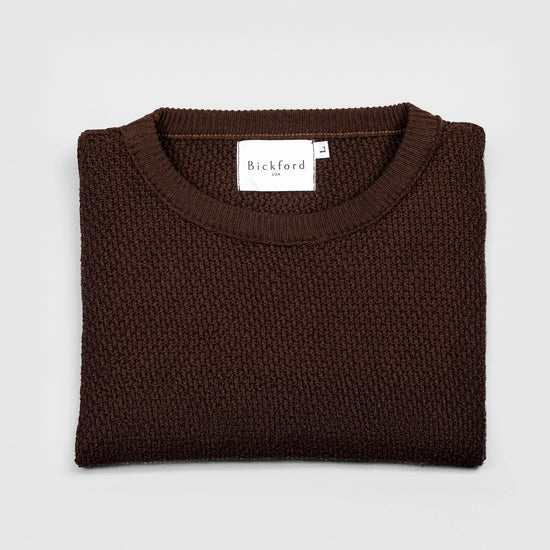 Bickford USA Fisherman sweater in dark brown, neatly folded and photographed from above, with the Bickford USA label visible at the center of the neckline.