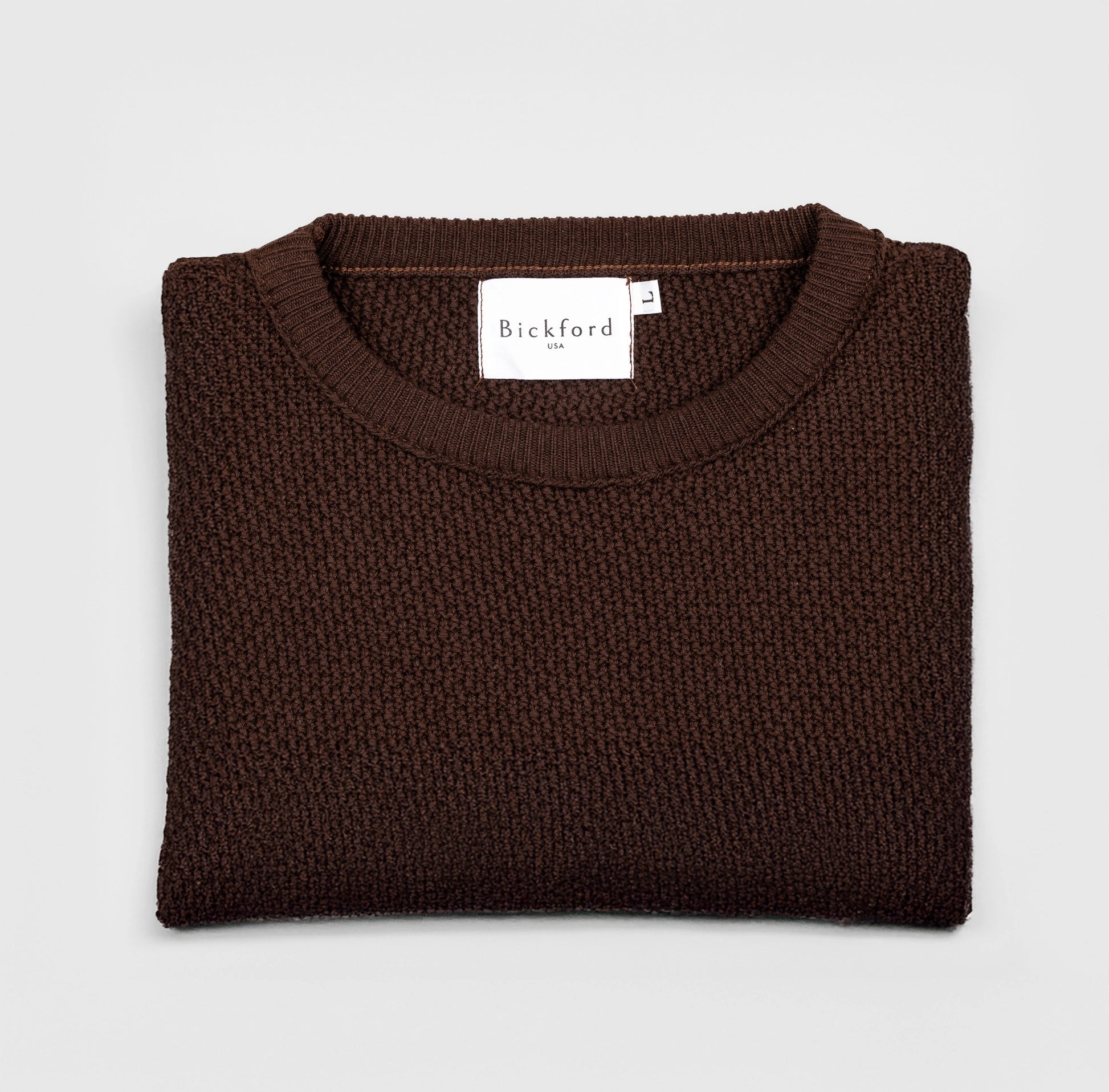 Bickford USA Fisherman sweater in dark brown, neatly folded and photographed from above, with the Bickford USA label visible at the center of the neckline.