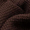 Extreme macro close-up of the dark brown Fisherman sweater fabric, showing the chunky seed stitch texture and dense yarn construction in detail.