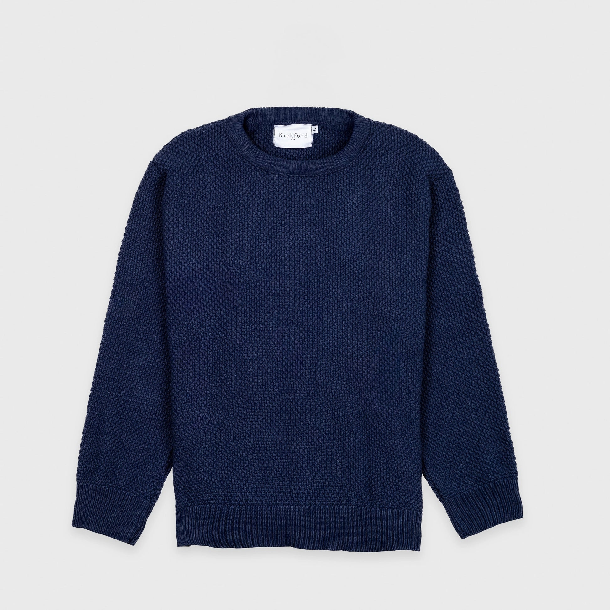 Bickford USA Fisherman sweater in navy, laid flat on a light gray background, showing the full front with seed stitch knit texture and ribbed crew neck, cuffs, and hem.