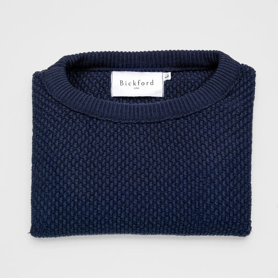 Bickford USA Fisherman sweater in navy, neatly folded and photographed from above, with the Bickford USA label visible at the center of the neckline.