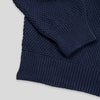 Close-up detail of the navy Fisherman sweater showing the folded hem and cuff, highlighting the contrast between the seed stitch body fabric and the ribbed knit trim.