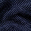 Extreme macro close-up of the navy Fisherman sweater fabric, showing the chunky seed stitch knit texture and soft yarn fibers in detail.