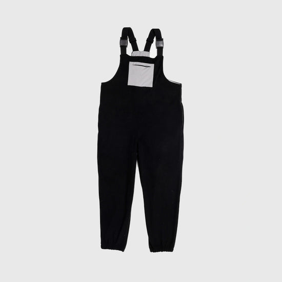 Bickford USA fleece overall bib in black, front view, featuring adjustable shoulder straps with Fidlock buckles and a gray chest pocket with zipper, against a light gray background.