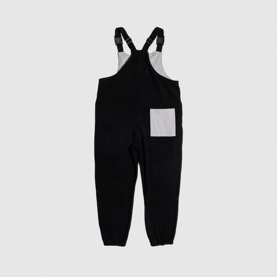 Bickford USA fleece overall bib in black, back view, showing a gray square back pocket and elastic cuffed ankles, against a light gray background.