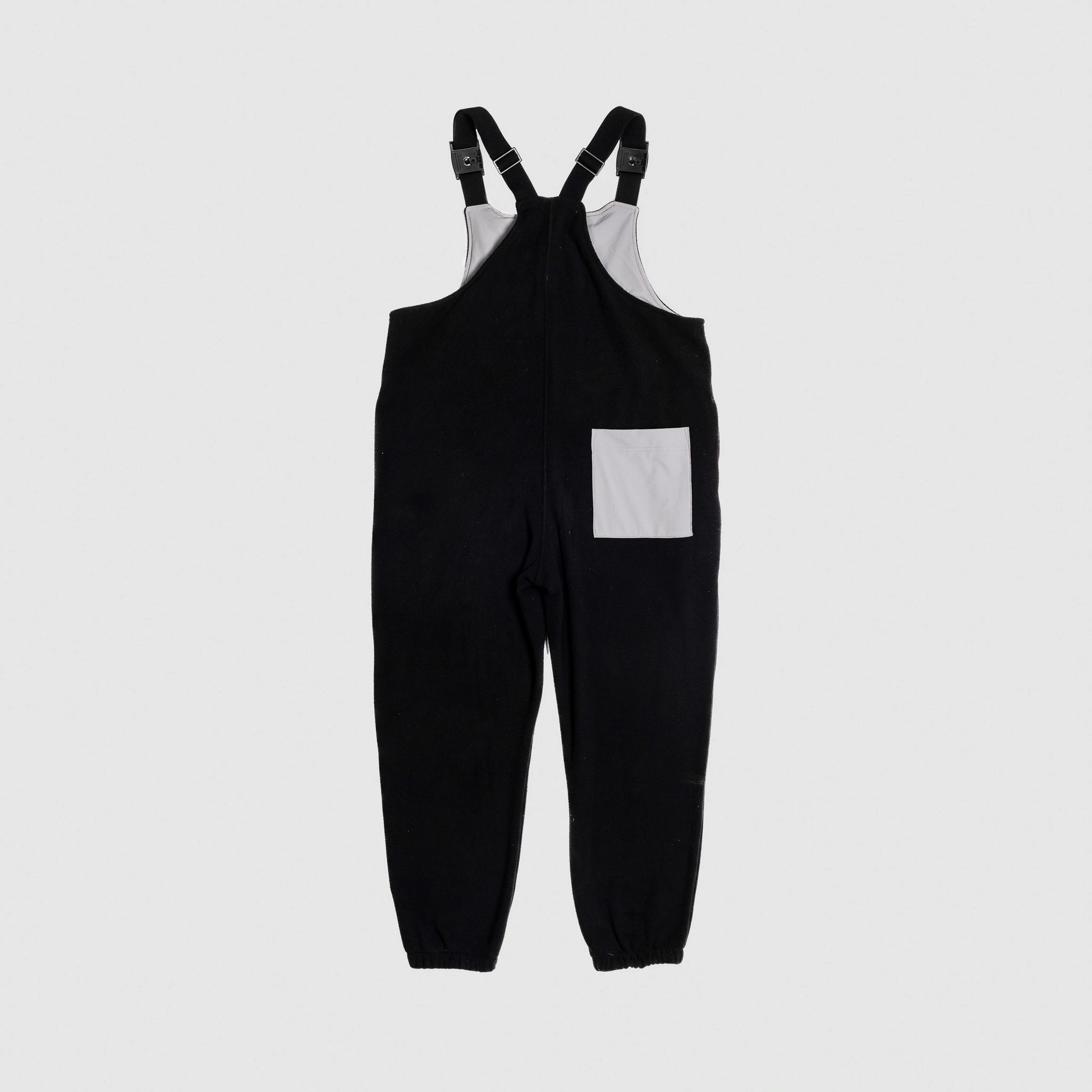 Bickford USA fleece overall bib in black, back view, showing a gray square back pocket and elastic cuffed ankles, against a light gray background.