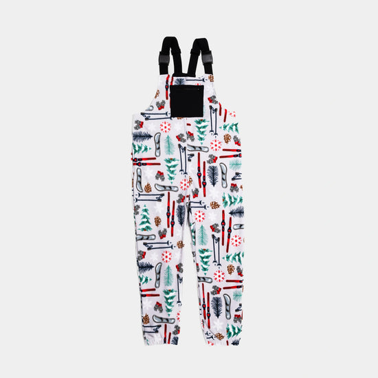 Bickford USA fleece overall bib in the Sugarbush colorway — a white base with an allover winter ski resort print featuring red skis, ski poles, snowboards, evergreen trees, pine cones, ski gloves, and red snowflakes — front view with black chest pocket and Fidlock buckles, against a light gray background.