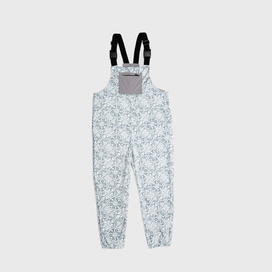 Bickford USA fleece overall bib in the Snowflake colorway — a soft blue-gray base with an allover white floral and snowflake lattice print — front view with gray chest pocket and Fidlock buckles, against a light gray background.