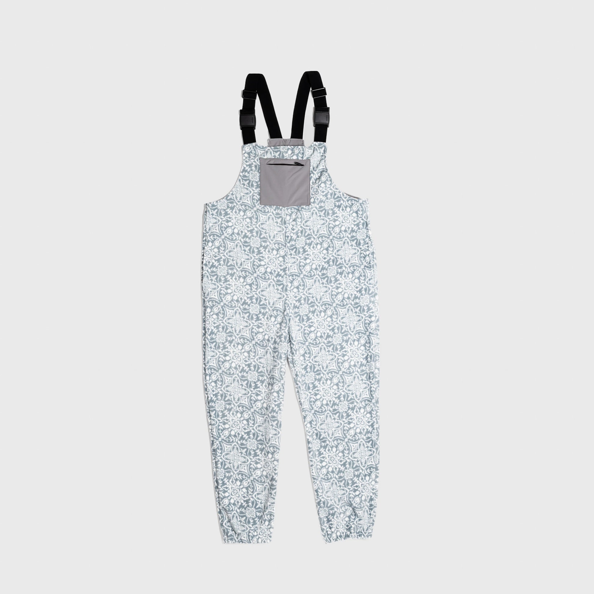 Bickford USA fleece overall bib in the Snowflake colorway — a soft blue-gray base with an allover white floral and snowflake lattice print — front view with gray chest pocket and Fidlock buckles, against a light gray background.