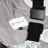 Close-up detail of a Bickford USA label with size S tag and Fidlock magnetic buckle hardware on the Snowflake colorway overall bib, with gray interior lining and the blue-gray snowflake-print fleece visible.