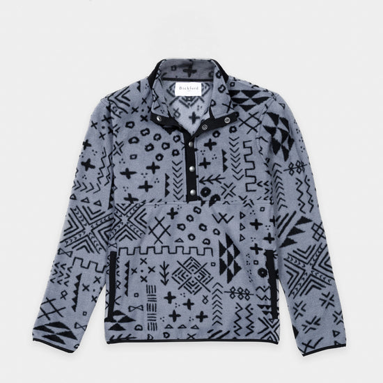 Bickford USA quarter-snap fleece pullover in the Boulder colorway — a gray base with an allover black geometric and tribal print — flat lay front view, featuring a black grosgrain placket with silver snap buttons and matching trim, against a light gray background.