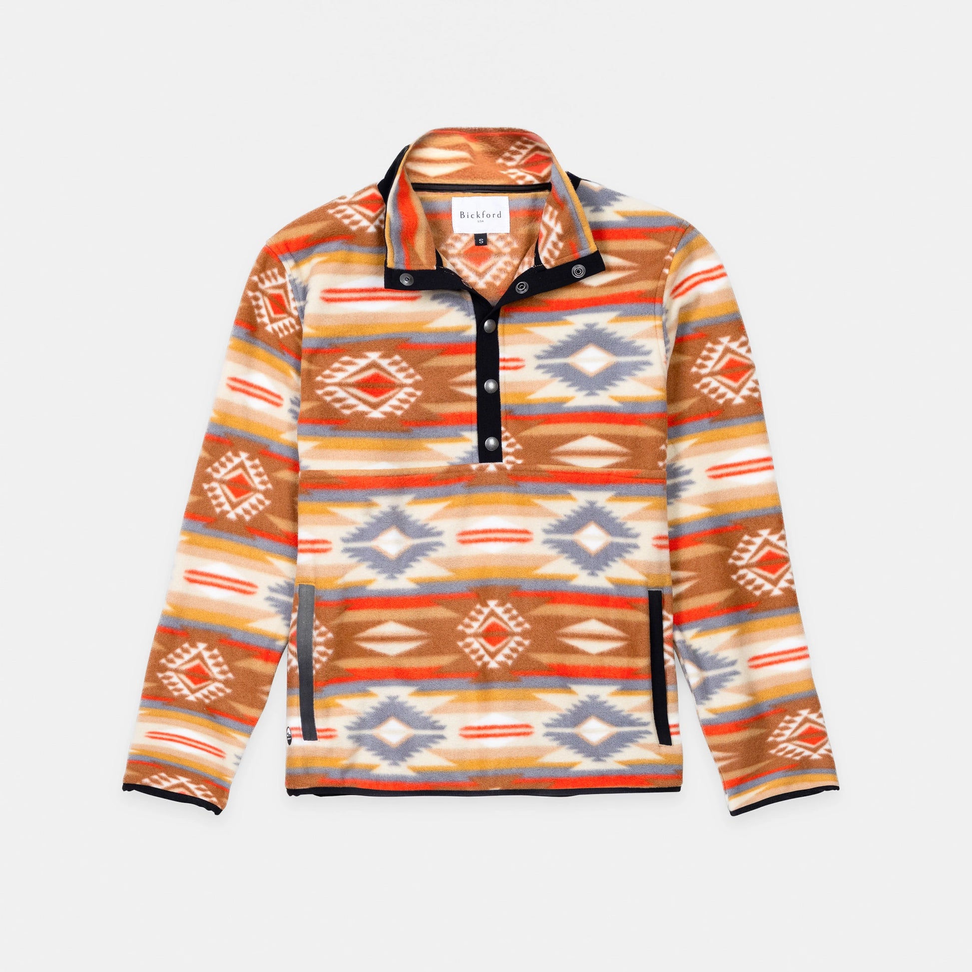 Bickford USA quarter-snap fleece pullover in the Heritage Trail colorway — a Southwestern-inspired pattern in warm tones of tan, rust, orange, gold, cream, and slate blue — flat lay front view, featuring a black grosgrain placket with silver snap buttons and matching trim, against a light gray background.