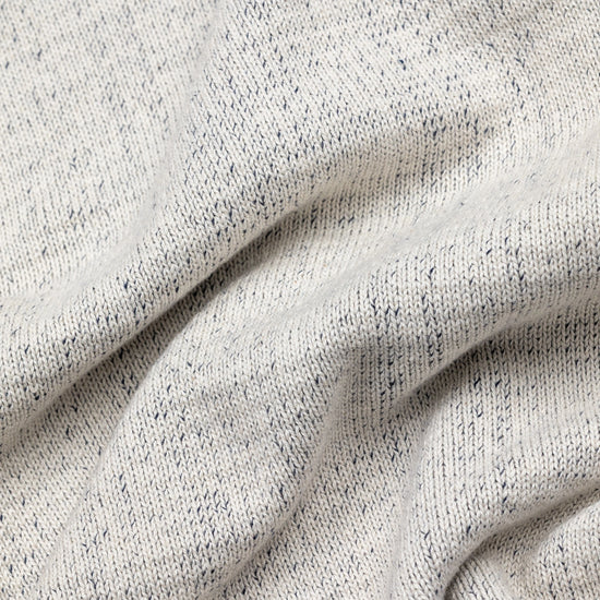 Extreme macro close-up of The 1926 Sweater fabric in natural and grey, showing the fine marled knit texture with natural cream yarn flecked throughout with dark grey.