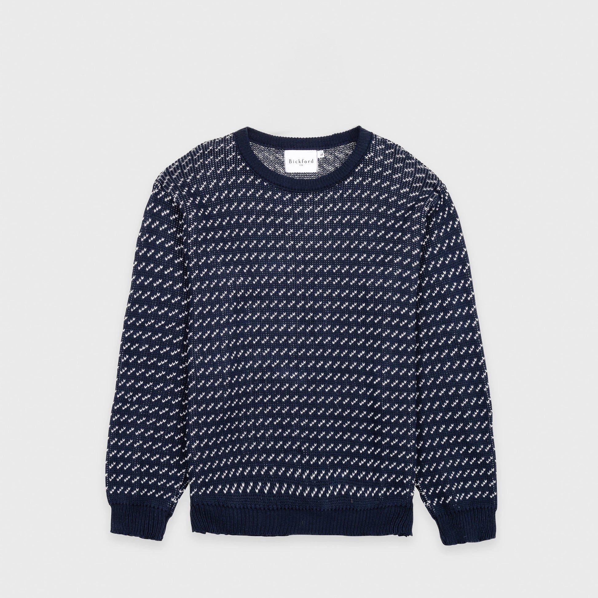 Bickford USA The 1926 Sweater in navy and natural, laid flat on a light gray background, showing the full front with an all-over diagonal birdseye knit pattern in navy and white and a solid navy ribbed crew neck, cuffs, and hem.