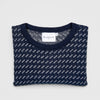 Bickford USA The 1926 Sweater in navy and natural, neatly folded and photographed from above, with the Bickford USA label visible at the center of the solid navy ribbed neckline and the birdseye pattern visible on the body.