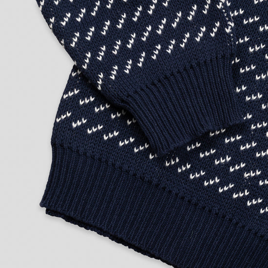Close-up detail of The 1926 Sweater in navy and natural showing the folded hem and cuff area, highlighting the contrast between the diagonal birdseye patterned body and the solid navy ribbed trim.