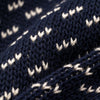Extreme macro close-up of The 1926 Sweater fabric in navy and natural, showing the diagonal birdseye knit stitch detail with cream-colored V-shaped floats against a deep navy background.
