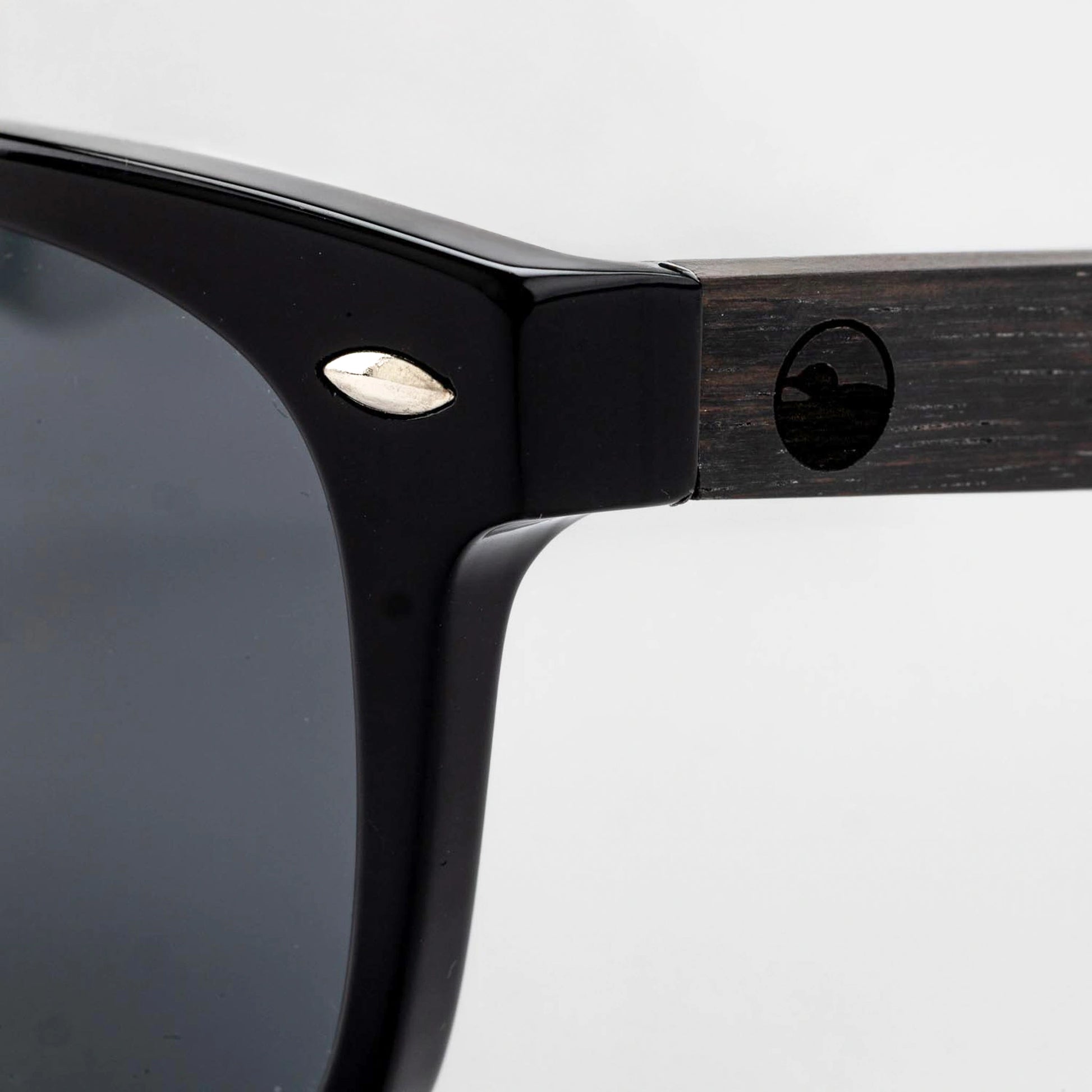 Close-up of the Bickford USA Timberline Full-Frame Sunglasses temple in midnight black, showing the wood temple inlay and engraved loon logo.