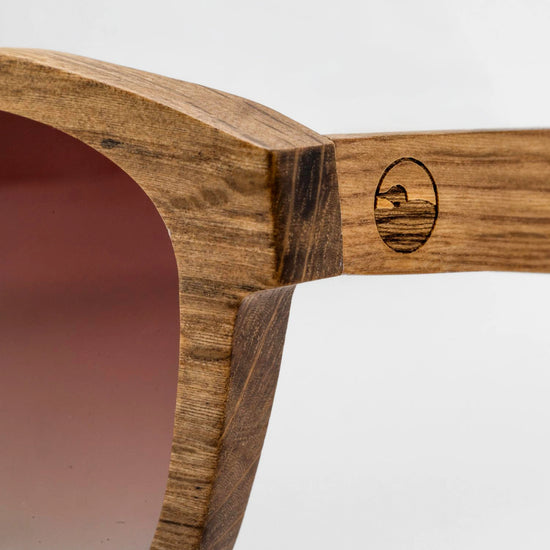 Close-up of the Bickford USA Timberline Full-Frame Sunglasses temple in natural zebrano wood, showing the wood grain and engraved loon logo.