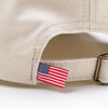 Close-up of American flag tag and antique brass buckle strap on Bickford Natural chino cap