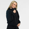 Woman wearing the black Women's Cropped Quarter-Zip fleece pullover, shown from the waist up in a three-quarter pose holding the collar closed with one hand, paired with matching black fleece pants against a light gray background.