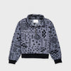 Bickford USA Women's Cropped Quarter-Zip fleece pullover in the Boulder colorway, laid flat on a light gray background, featuring an all-over black geometric tribal print on a grey background, with a wide fold-over collar, brass quarter-zip closure, front kangaroo pocket, and contrasting black ribbed hem and cuffs.