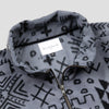 Close-up detail of the Boulder Women's Cropped Quarter-Zip showing the open fold-over collar with the Bickford USA label and size tag visible inside, and the brass zipper pull partially unzipped against the grey and black geometric tribal print.