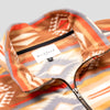 Close-up detail of the Heritage Trail Women's Cropped Quarter-Zip showing the open fold-over collar with the Bickford USA label and size tag visible inside, and the brass zipper pull partially unzipped against the southwestern geometric print in orange, brown, and grey.