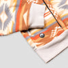 Close-up of the lower hem and kangaroo pocket area of the Heritage Trail Women's Cropped Quarter-Zip, showing the contrasting cream ribbed hem band, the pocket opening with a knit tab detail, and the small circular Bickford logo patch against the southwestern stripe and geometric pattern.