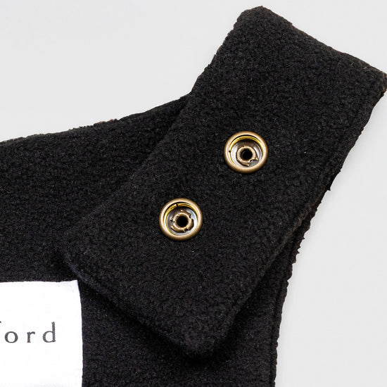 Close-up detail of the black Youth Overalls showing the adjustable shoulder strap with two brass snap closures and the Bickford USA label partially visible at the back of the neckline.