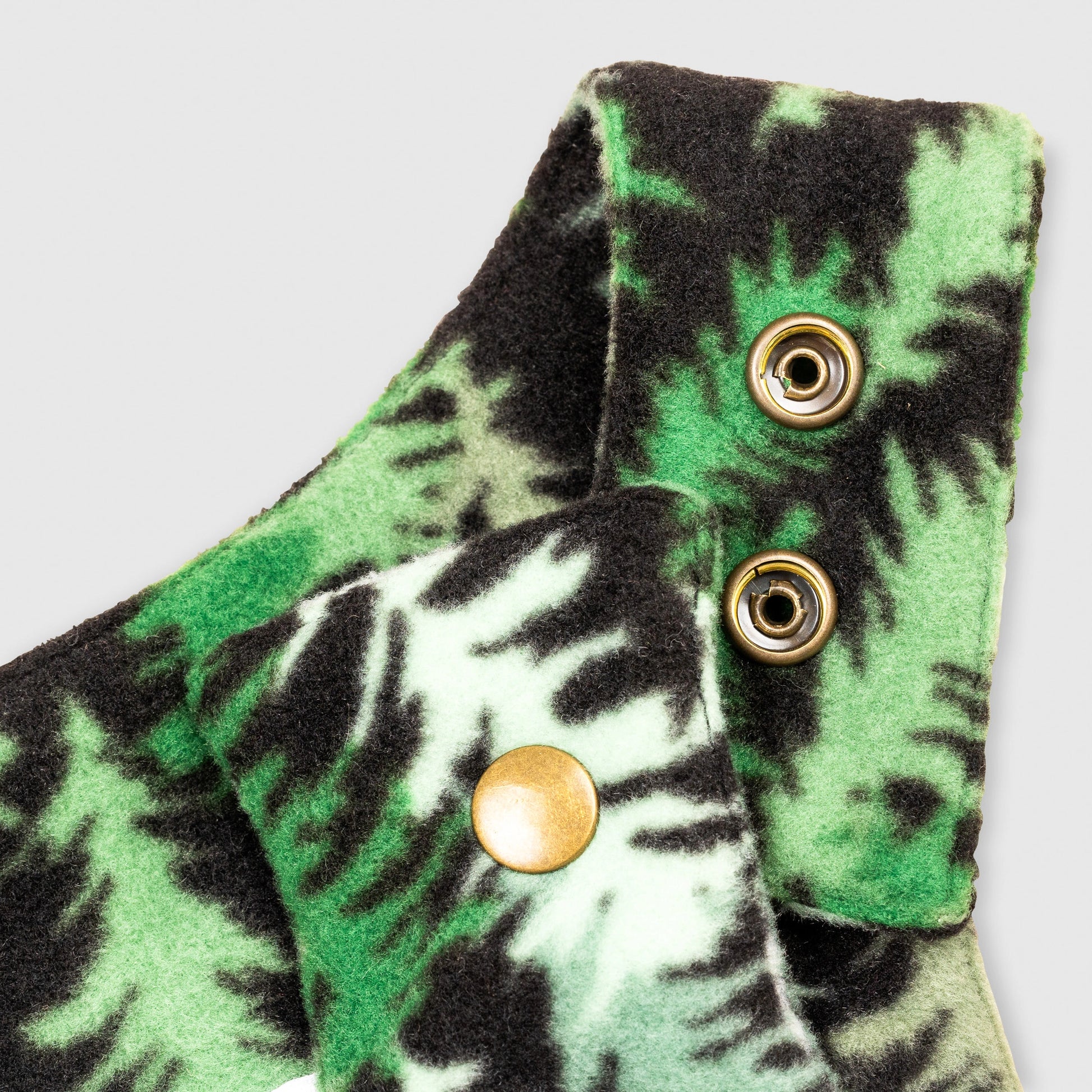 Close-up detail of the Eastern Pine Youth Overalls showing the adjustable shoulder strap with brass snap closures against the green and black pine tree print.