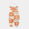 Bickford USA Youth fleece overalls in the Heritage Trail colorway, laid flat on a light gray background, featuring an all-over southwestern-style print with diamond and geometric motifs in orange, brown, red, grey, cream, and gold, with brass snap shoulder straps, a chest bib pocket with circular Bickford logo patch, two side pockets, and elasticized ankle cuffs.