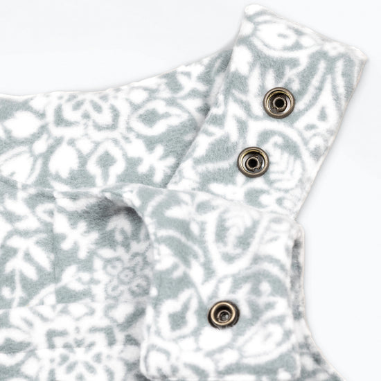 Close-up detail of the Snowflake Youth Overalls showing the adjustable shoulder straps with gunmetal snap closures against the grey and white ornate medallion print.