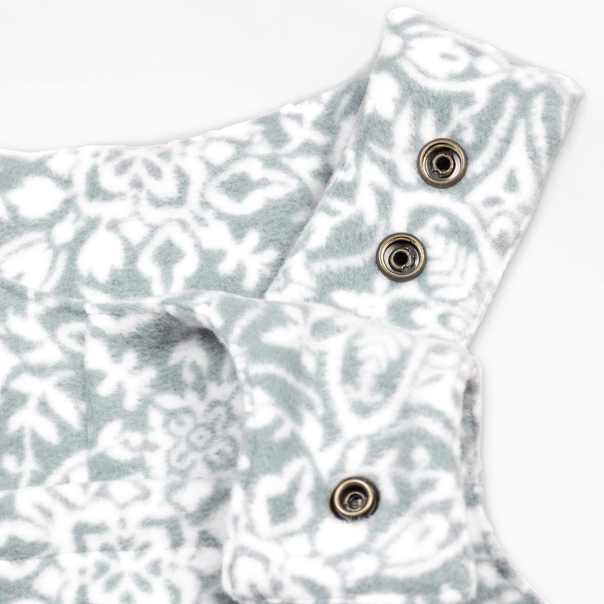 Close-up detail of the Snowflake Youth Overalls showing the adjustable shoulder straps with gunmetal snap closures against the grey and white ornate medallion print.