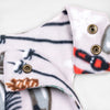 Close-up detail of the Sugarbush Youth Overalls showing the adjustable shoulder straps with brass snap closures against the winter sports print featuring skis, poles, and ice skates.