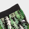 Close-up detail of the Eastern Pine Youth Pants showing the wide black elastic waistband, angled side pocket, and circular woven Bickford mountain logo patch against the green and black pine tree print.