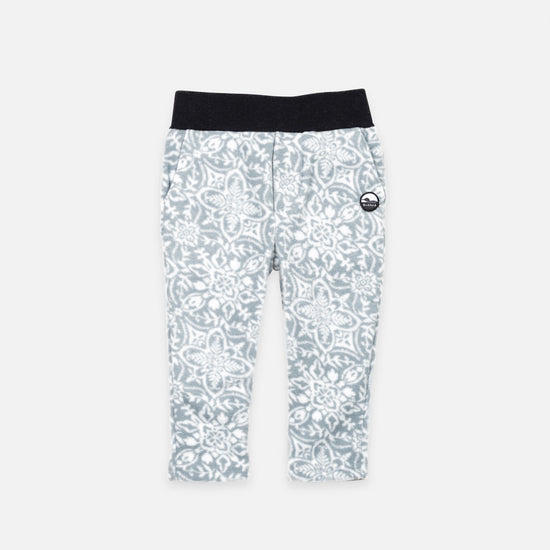 Bickford USA Youth fleece pants in the Snowflake colorway, laid flat on a light gray background, featuring an all-over ornate snowflake and medallion print in grey and white, with a wide black elastic waistband, side hand pockets, and circular Bickford logo patch on the hip.