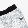 Close-up detail of the Snowflake Youth Pants showing the wide black elastic waistband, angled side pocket, and circular woven Bickford mountain logo patch against the grey and white ornate snowflake medallion pattern.