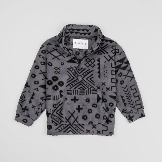 Bickford USA Youth Quarter-Zip fleece pullover in the Boulder colorway, laid flat on a light gray background, featuring an all-over black geometric tribal print on a grey background, with a funnel collar, quarter-zip closure, and front kangaroo pocket.
