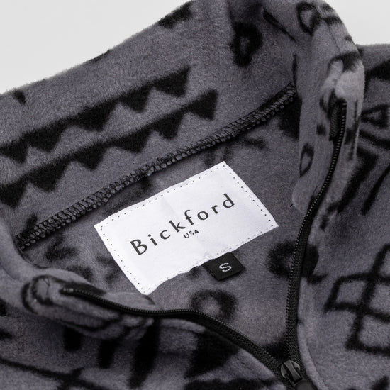 Close-up detail of the Boulder Youth Quarter-Zip showing the open funnel collar with the Bickford USA label and size tag visible, revealing the geometric tribal print on the inner collar and the black zipper.
